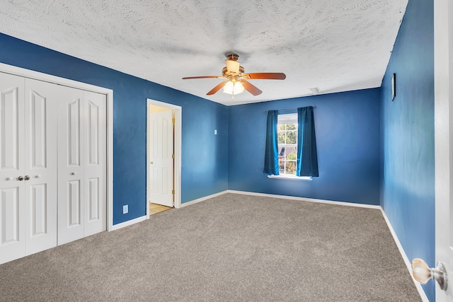 unfurnished bedroom with ceiling fan, carpet, a closet, and a textured ceiling