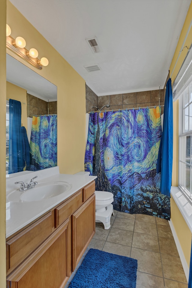 bathroom with a wealth of natural light, tile patterned flooring, toilet, and vanity