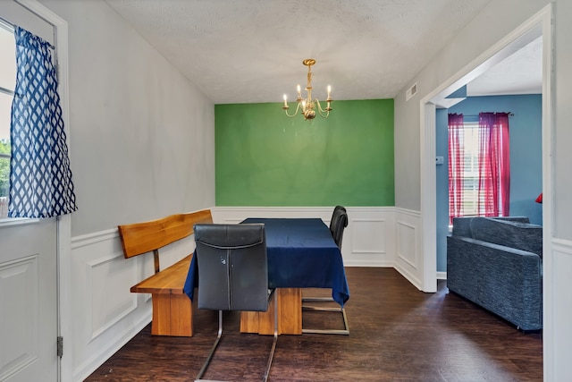 dining space featuring a textured ceiling, an inviting chandelier, and dark hardwood / wood-style floors