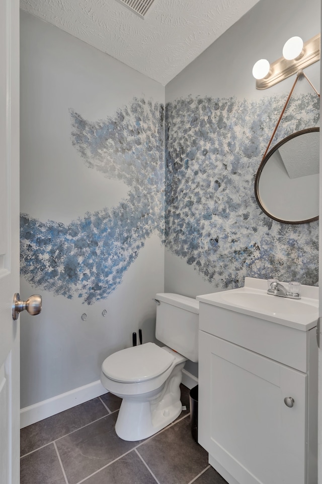 bathroom with tile patterned flooring, a textured ceiling, vanity, and toilet