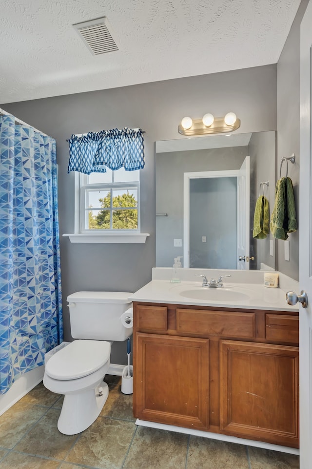 bathroom with toilet, tile patterned flooring, vanity, walk in shower, and a textured ceiling