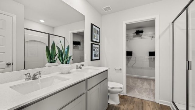 bathroom featuring hardwood / wood-style floors, toilet, vanity, and a shower with shower door