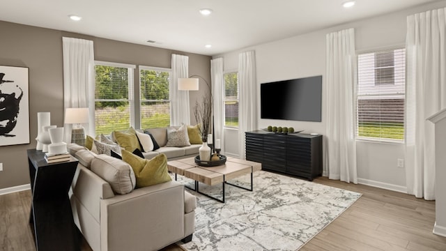 living room with a wealth of natural light and light hardwood / wood-style flooring