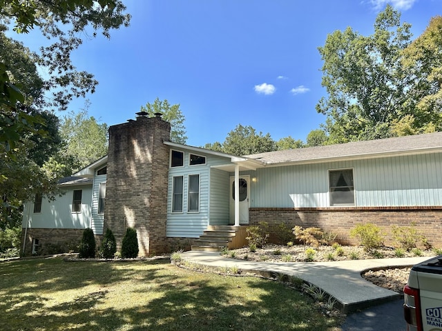 view of front of house with brick siding, a chimney, and a front lawn