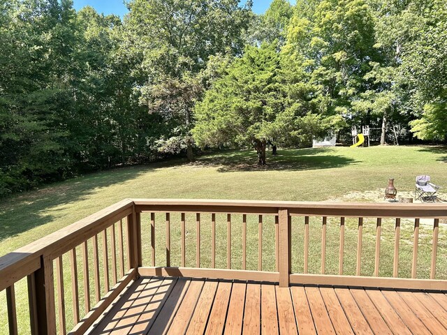 wooden terrace with a playground and a lawn