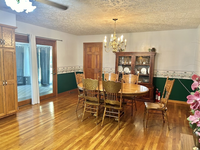 dining area with a textured ceiling, an inviting chandelier, and wood-type flooring