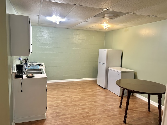 kitchen featuring light hardwood / wood-style flooring, fridge, a paneled ceiling, white refrigerator, and sink