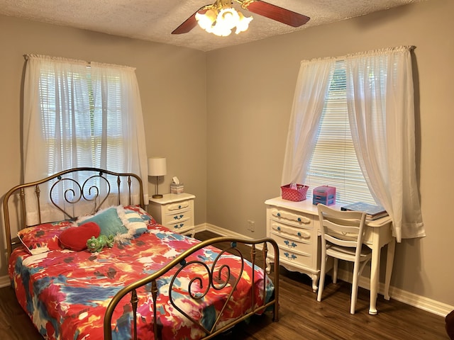 bedroom with a textured ceiling, ceiling fan, multiple windows, and dark hardwood / wood-style flooring