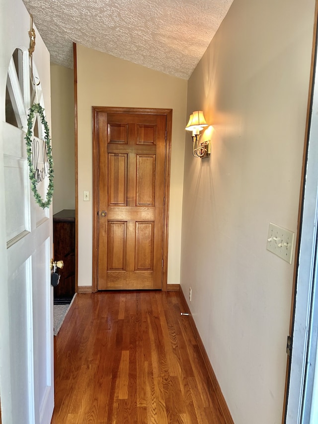 entryway with dark wood-type flooring, a textured ceiling, and lofted ceiling