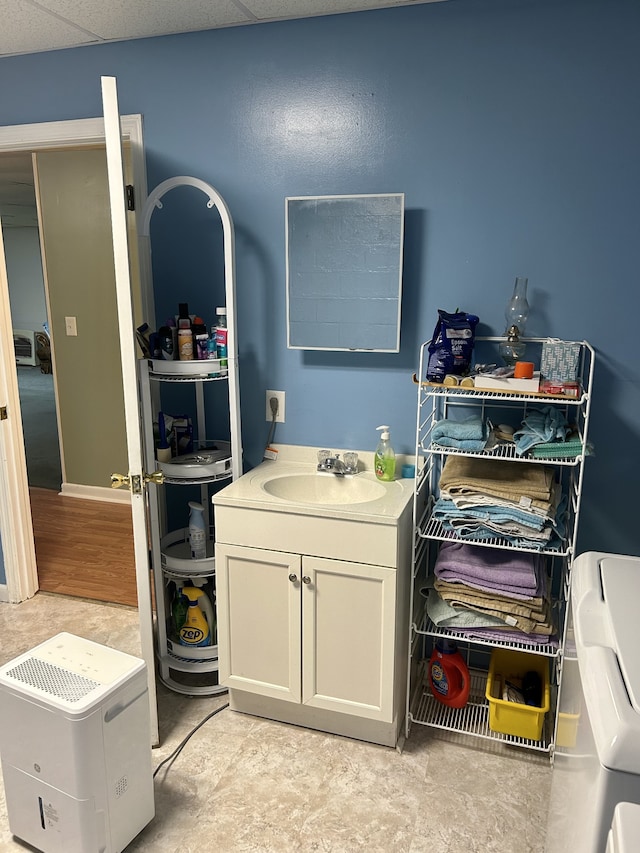 interior space with sink, washing machine and clothes dryer, light hardwood / wood-style flooring, and a drop ceiling