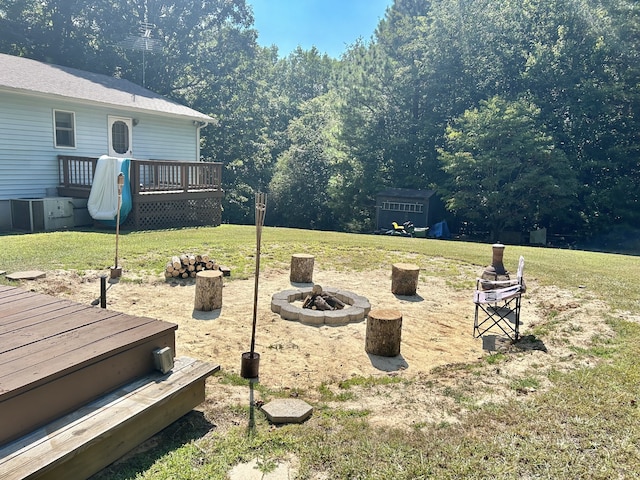 view of yard with a wooden deck, an outbuilding, and a fire pit