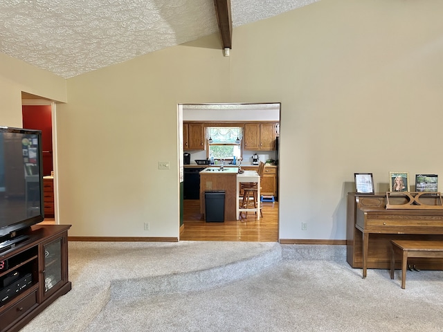 interior space featuring light wood-type flooring, vaulted ceiling with beams, and a textured ceiling