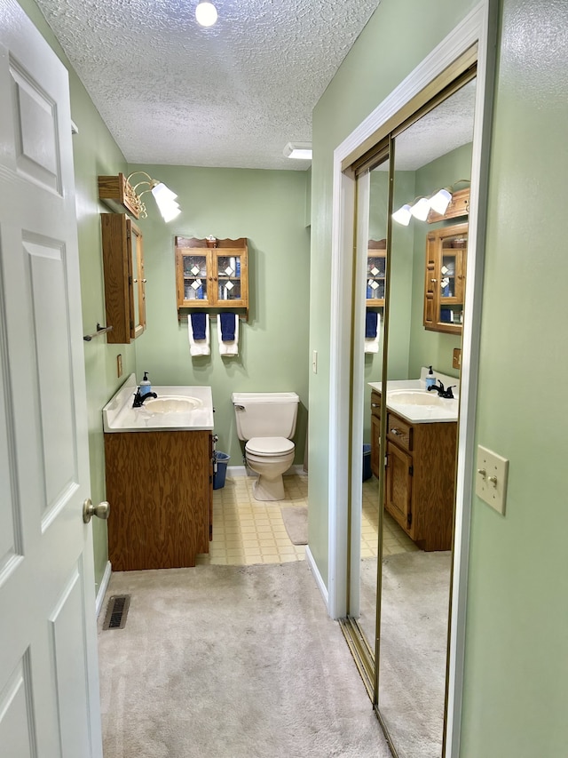 bathroom featuring tile patterned flooring, a textured ceiling, vanity, and toilet