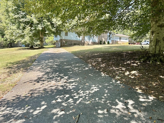 view of front facade featuring aphalt driveway, a front lawn, and stone siding