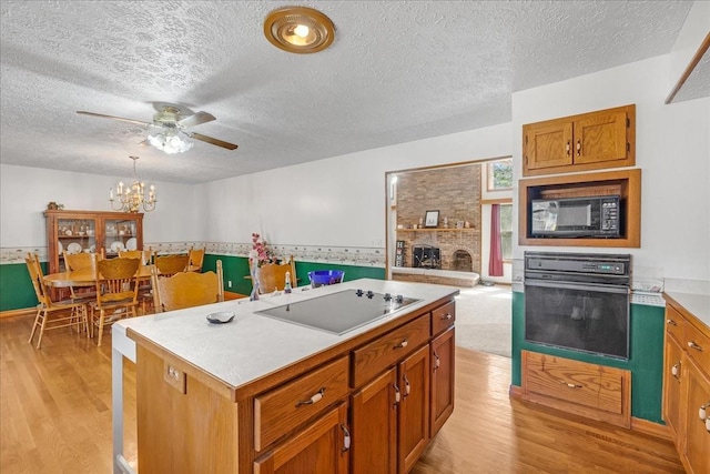 kitchen featuring black appliances, light countertops, light wood-type flooring, and a kitchen island