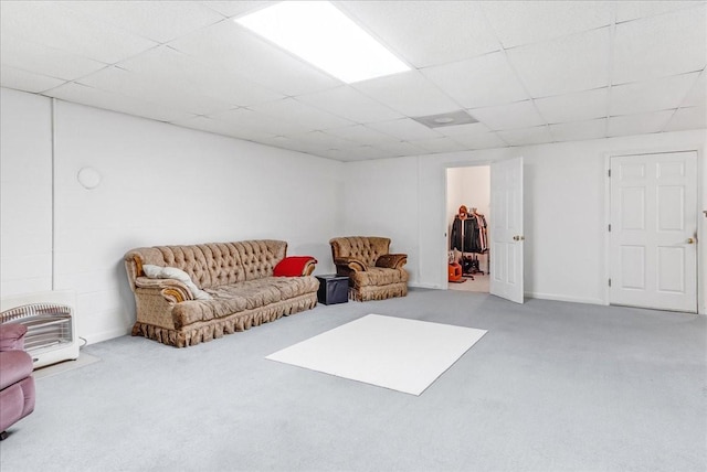 living area featuring heating unit, a paneled ceiling, and carpet