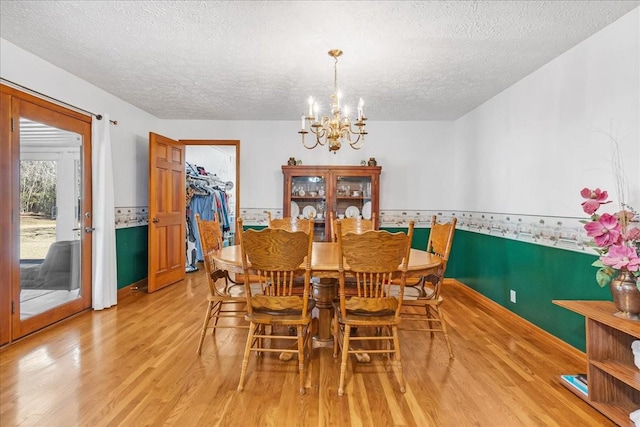 dining room with a notable chandelier, light wood-style floors, and a textured ceiling