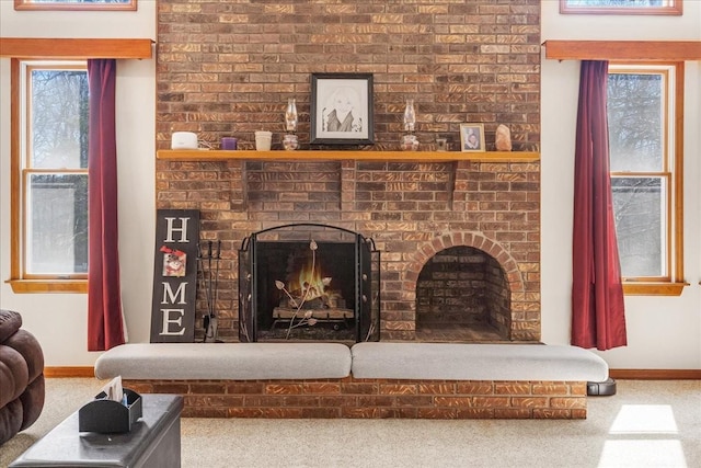 carpeted living area featuring a brick fireplace and baseboards