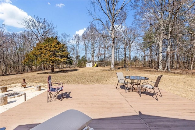 view of patio / terrace featuring a deck, an outdoor fire pit, a storage shed, and an outdoor structure