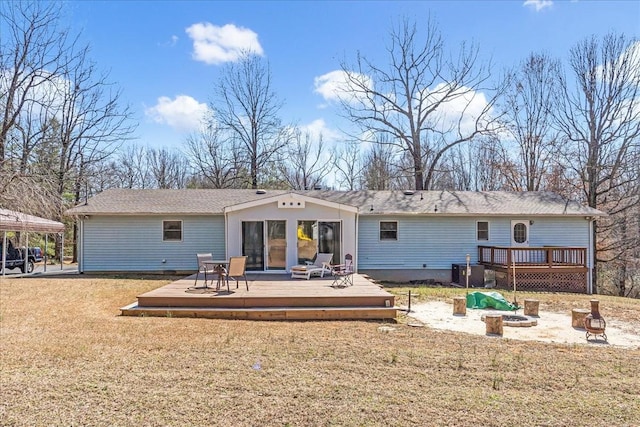 back of property with a deck, central air condition unit, a fire pit, and a lawn