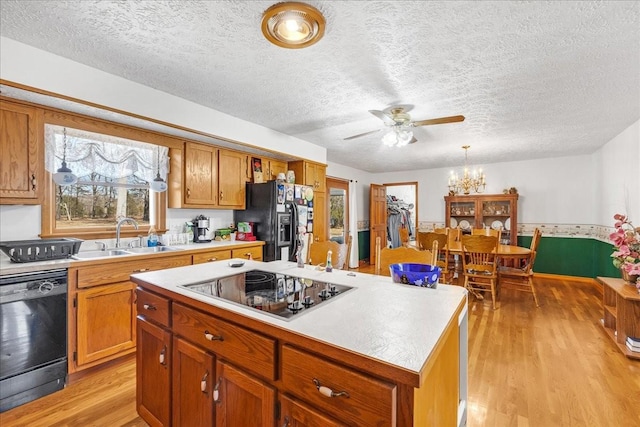 kitchen featuring a sink, light wood-style floors, black appliances, and light countertops