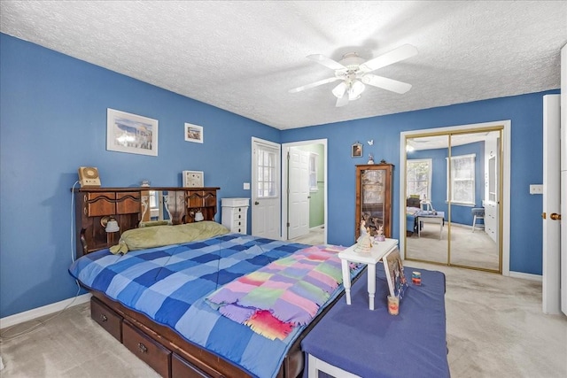 bedroom with a ceiling fan, baseboards, a closet, a textured ceiling, and light colored carpet