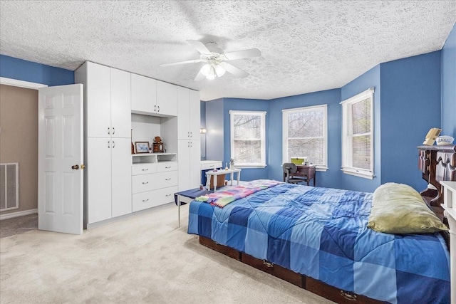 bedroom with light carpet, visible vents, a textured ceiling, and a ceiling fan