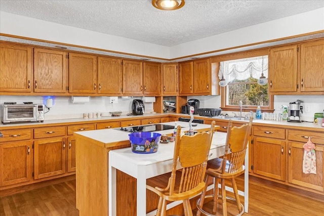 kitchen with light countertops, wood finished floors, and brown cabinets