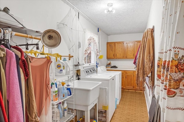 laundry area with washer and dryer, cabinet space, light floors, and a textured ceiling