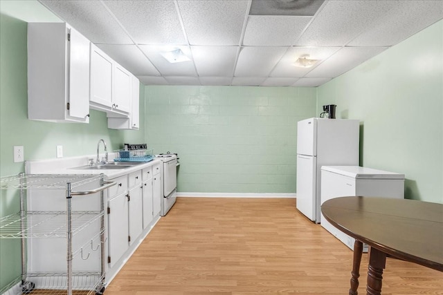 kitchen with white appliances, a sink, light countertops, white cabinets, and light wood-type flooring