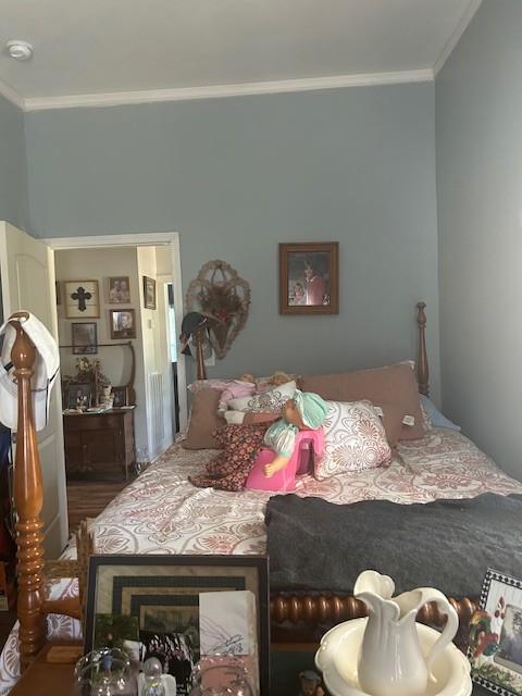 bedroom featuring ornamental molding and wood finished floors