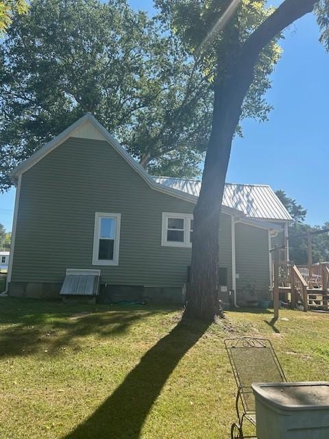 back of property featuring metal roof, a yard, and a standing seam roof