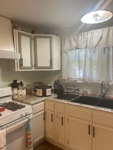 kitchen featuring custom exhaust hood, light countertops, white gas stove, white cabinetry, and a sink