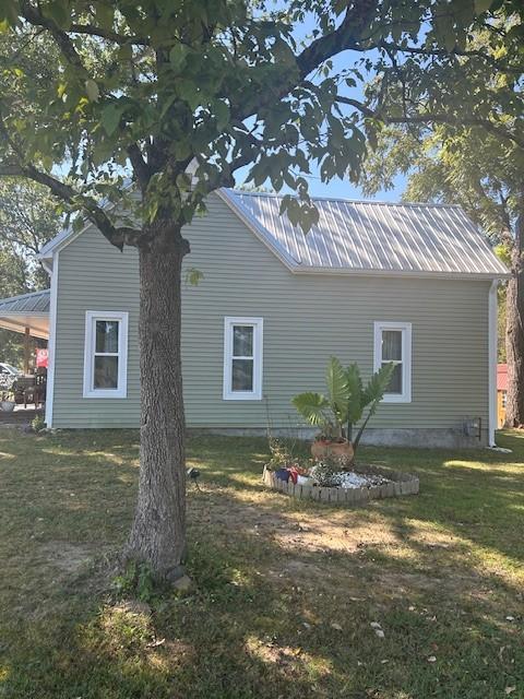 view of side of home with metal roof and a yard