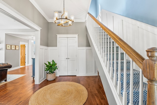 foyer entrance with crown molding, dark hardwood / wood-style floors, and an inviting chandelier