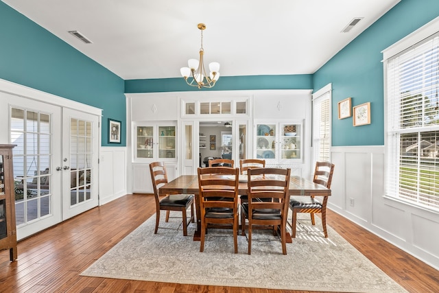 dining area featuring light wood-type flooring, french doors, a notable chandelier, and a healthy amount of sunlight