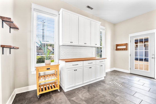 kitchen with butcher block counters, tile patterned floors, and white cabinetry