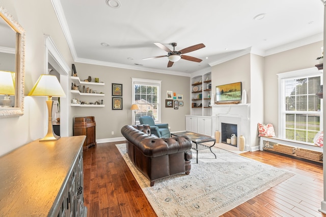 living room featuring built in features, crown molding, ceiling fan, and dark hardwood / wood-style flooring