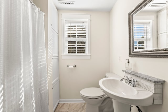 bathroom featuring tile patterned flooring, toilet, plenty of natural light, and sink