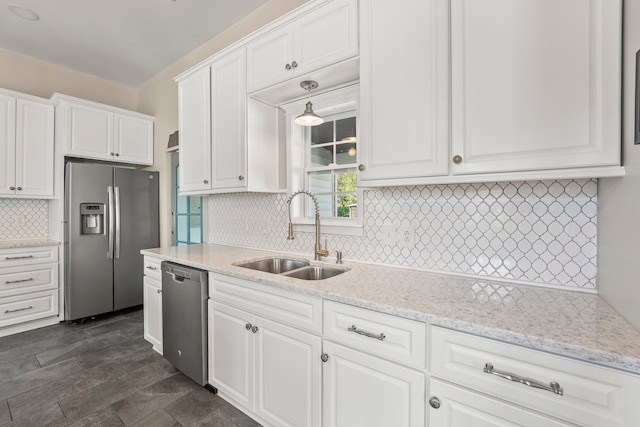 kitchen with backsplash, sink, light stone countertops, appliances with stainless steel finishes, and white cabinets