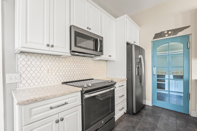 kitchen featuring stainless steel appliances, dark tile patterned floors, white cabinets, and tasteful backsplash