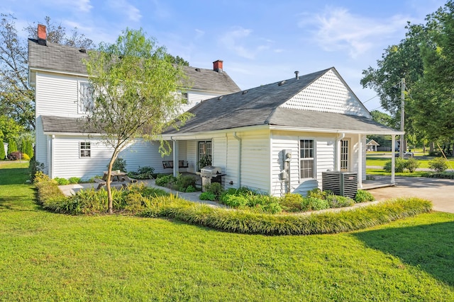 rear view of house featuring a lawn and central air condition unit