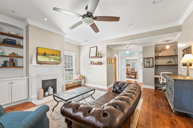 living room featuring built in shelves, dark wood-type flooring, ceiling fan, and ornamental molding