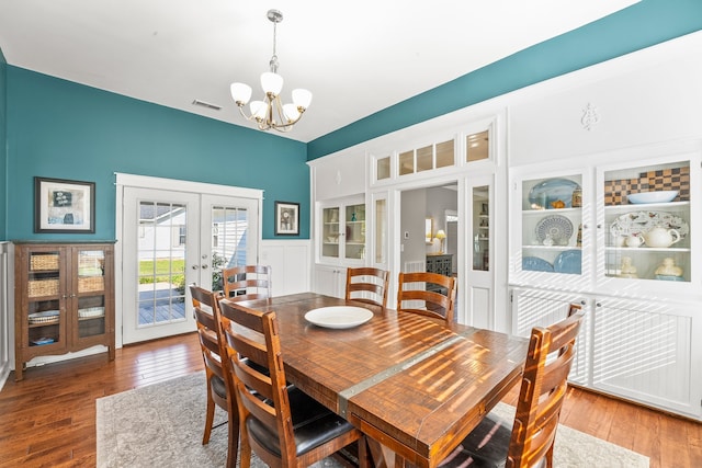 dining room with french doors, hardwood / wood-style flooring, and an inviting chandelier