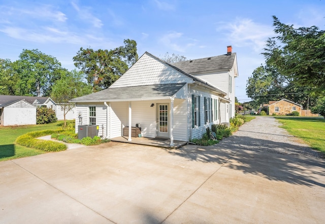 rear view of property with cooling unit and a lawn