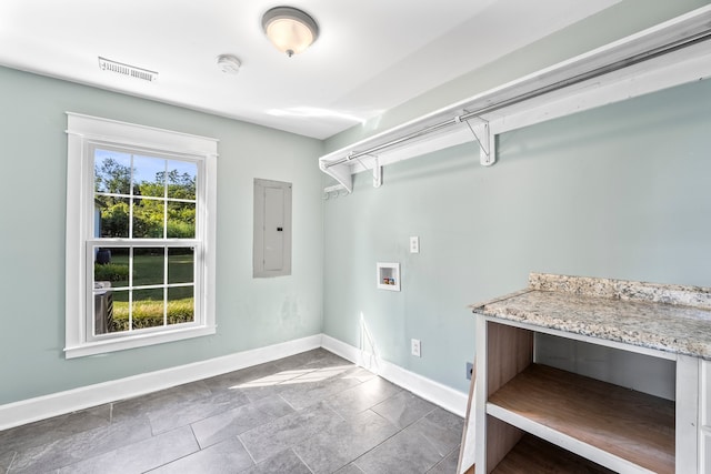 laundry area with electric panel, a wealth of natural light, hookup for a washing machine, and dark tile patterned floors