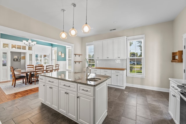 kitchen featuring backsplash, dark wood-type flooring, sink, a healthy amount of sunlight, and white cabinets