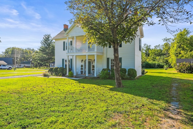 view of front of property featuring a balcony and a front yard