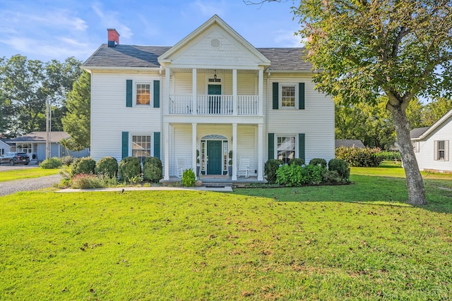 view of front facade featuring a balcony and a front yard