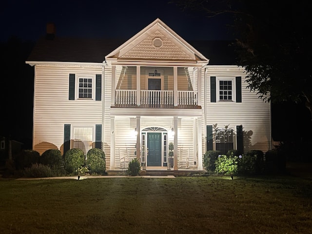 view of front of home with a balcony and a lawn